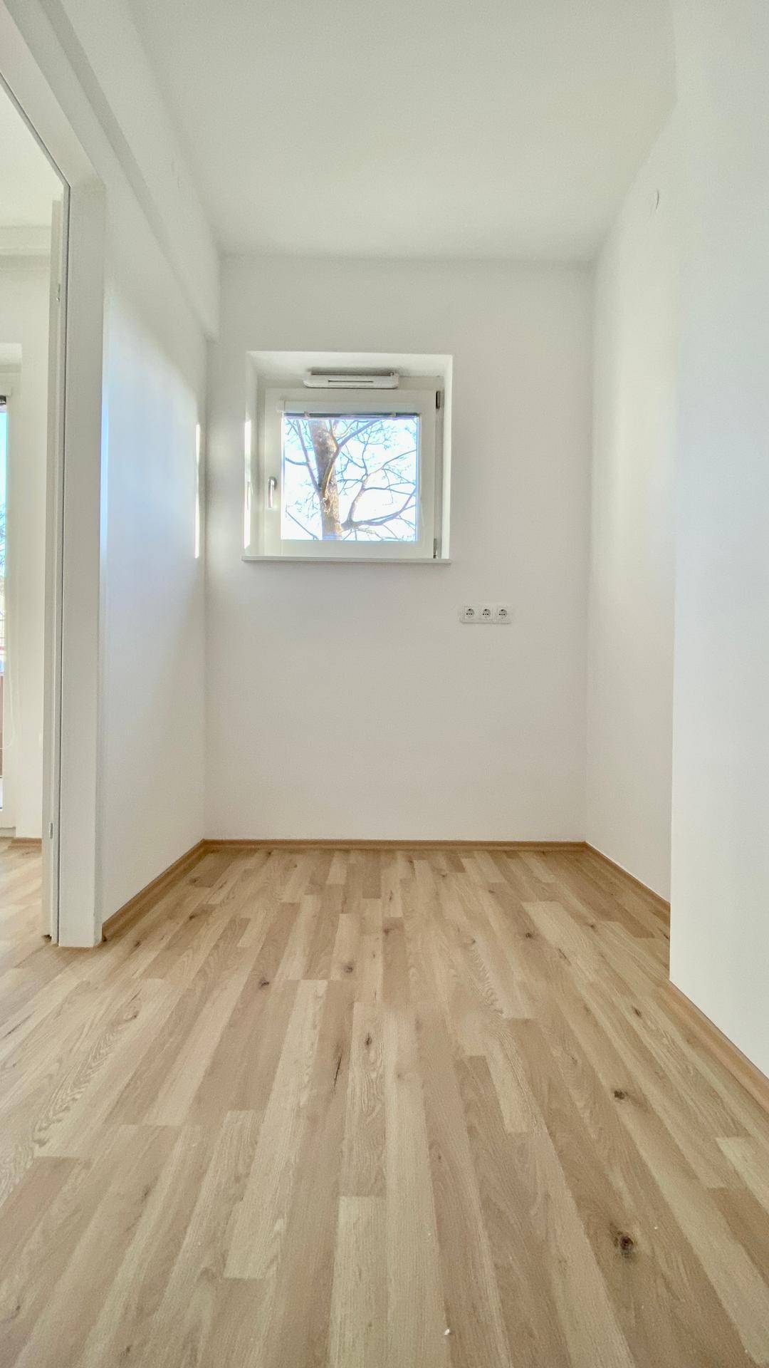 Kleiner Raum mit Parkettboden und Fenster, ideal als Büro oder Gästezimmer.