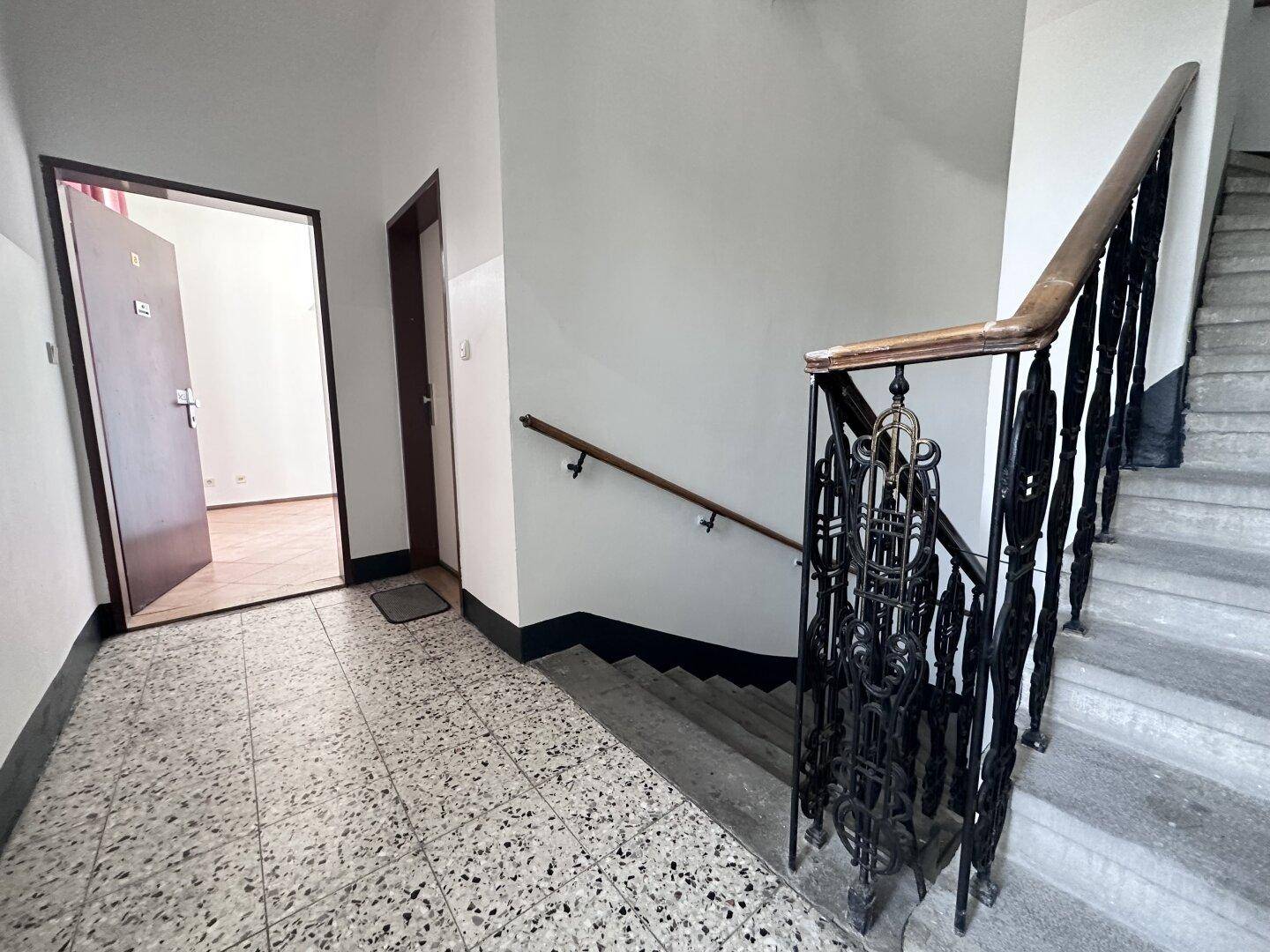 Historisches Treppenhaus mit Terrazzoboden und einem kunstvollen schmiedeeisernen Geländer.