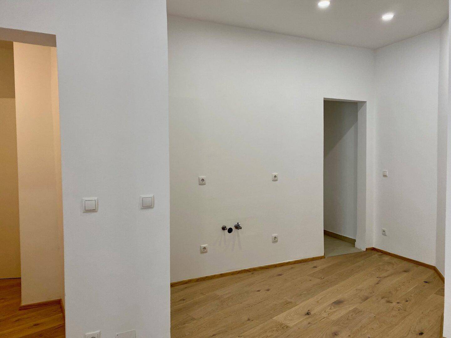 Leerer Raum mit Anschlüssen für eine Küche oder ein Badezimmer, bereit für den Ausbau.