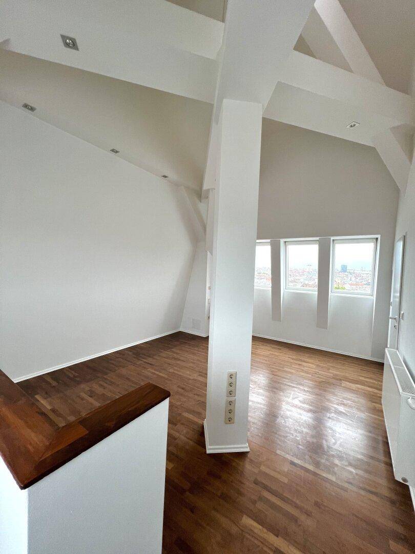 Heller Wohnraum mit Holzboden und Fenstern, die einen weiten Blick bieten.