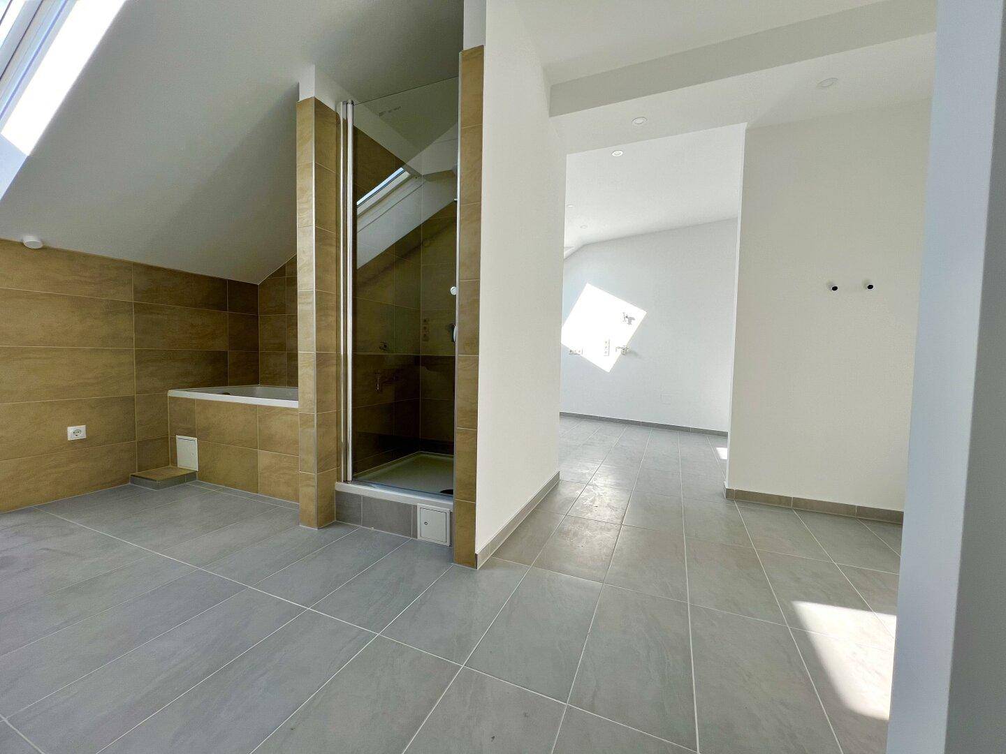 Modernes Badezimmer mit Dusche, Badewanne und Dachfenster, in warmen Farbtönen.