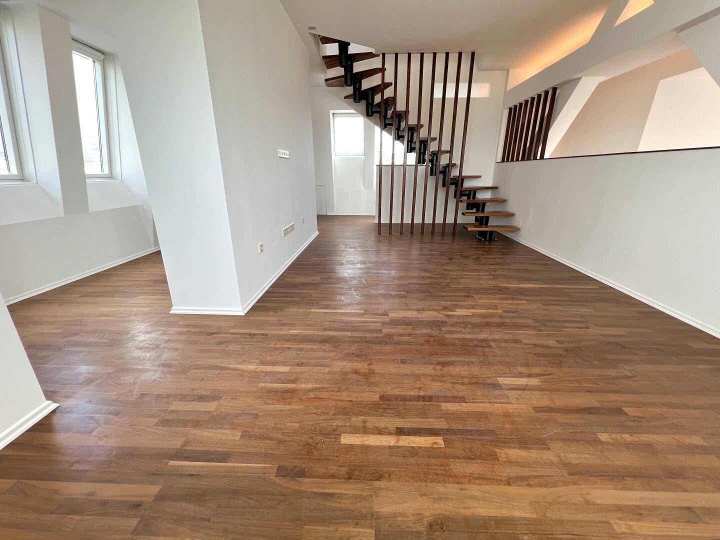Helles Wohnzimmer mit Holzboden und moderner Treppe, bereit zur individuellen Gestaltung.