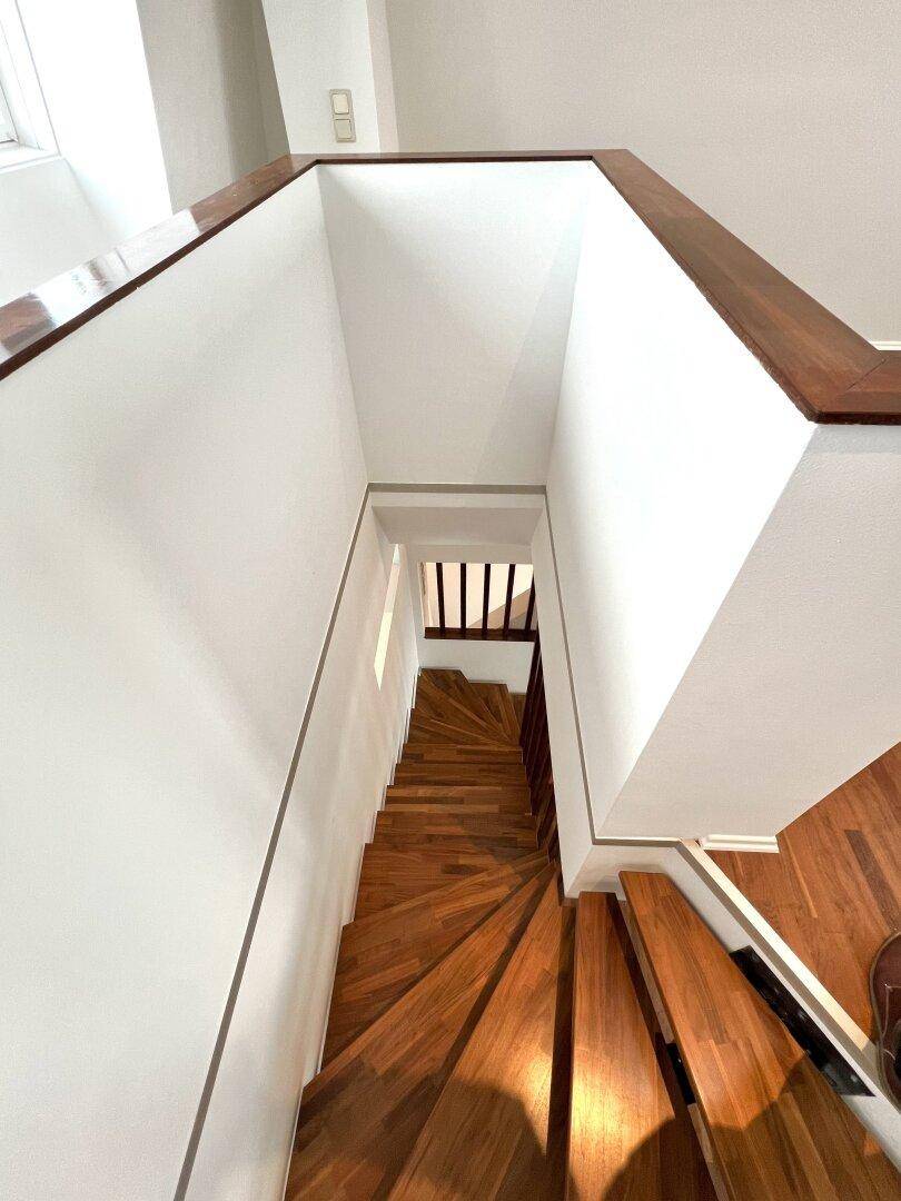 Blick von oben auf die elegante Holztreppe, die die verschiedenen Ebenen verbindet.