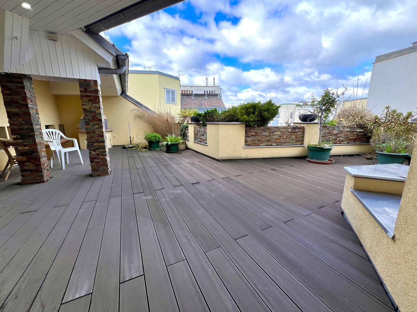 Weitläufige Dachterrasse mit Holzboden und Pflanzen, bietet viel Platz im Freien.
