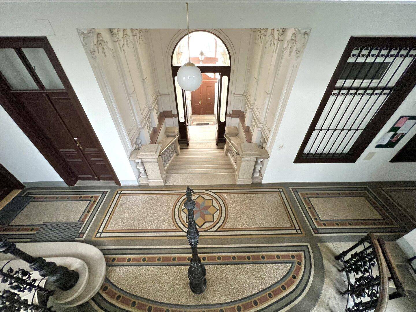 Prunkvoller Eingangsbereich mit hohen Decken, dekorativem Boden und eleganter Treppe.
