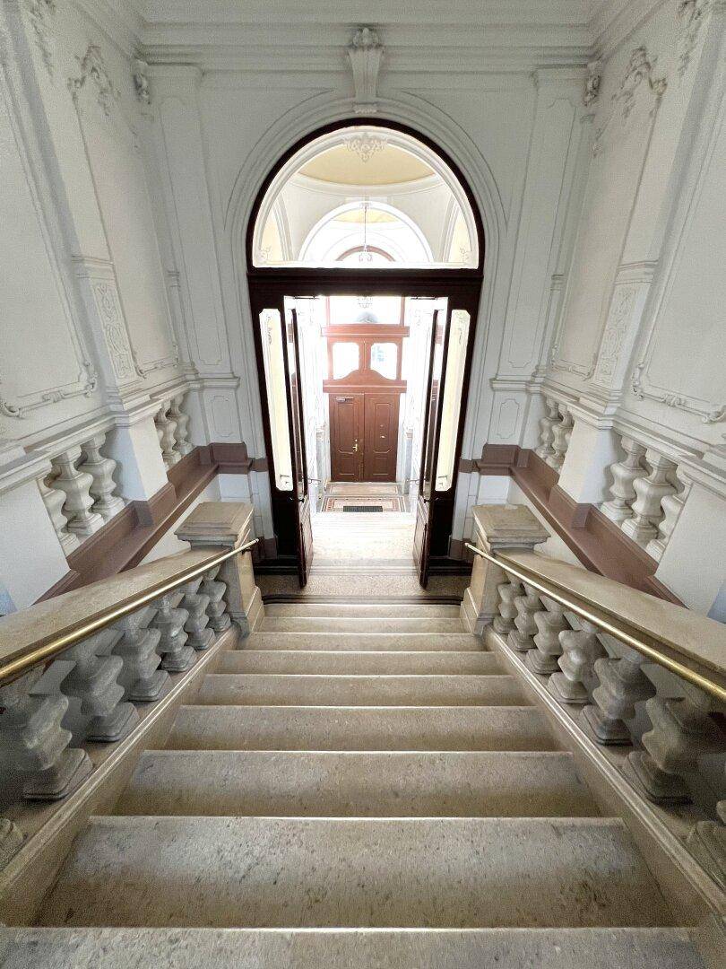 Majestätische Steintreppe mit kunstvollen Balustraden und einem beeindruckenden Torbogen.