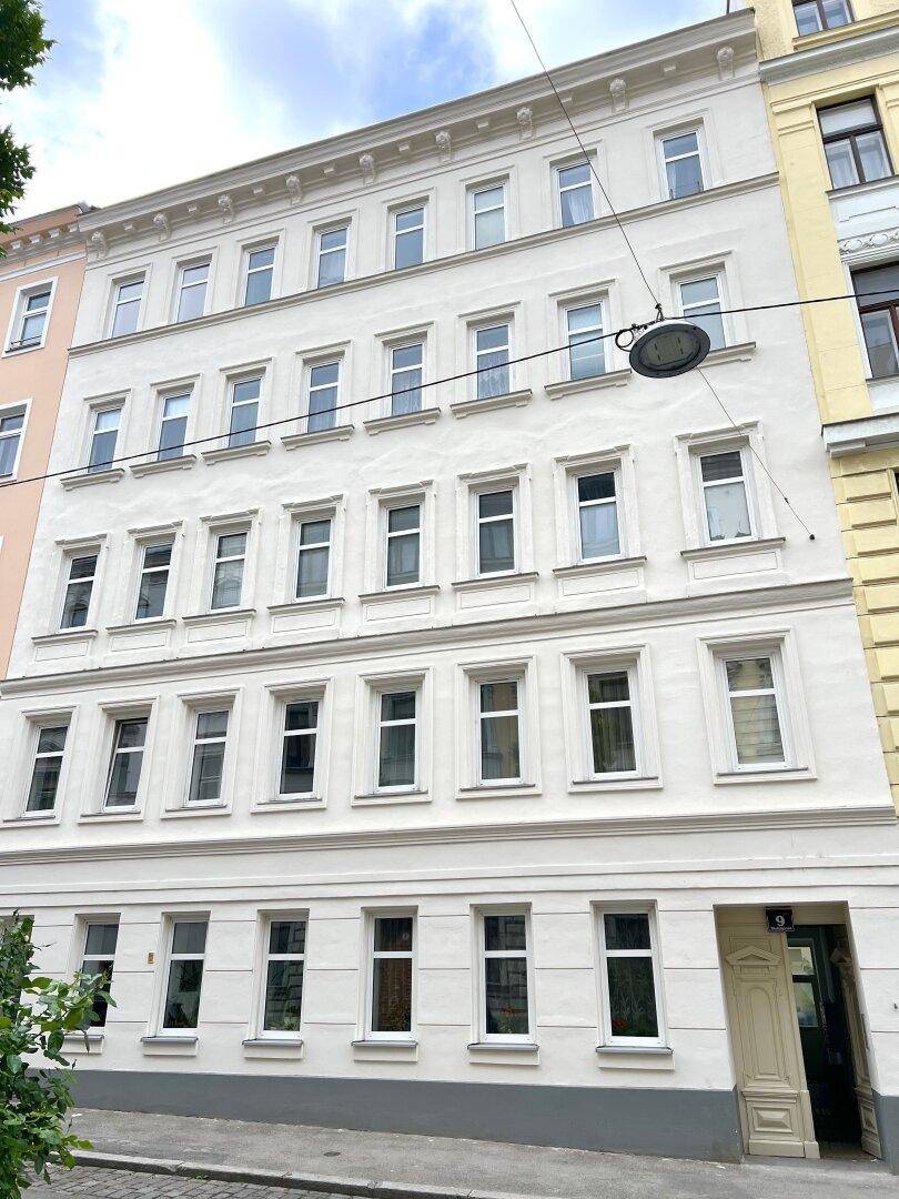 Klassische Altbaufassade mit vielen Fenstern und gepflegtem Erscheinungsbild in einer städtischen Umgebung.