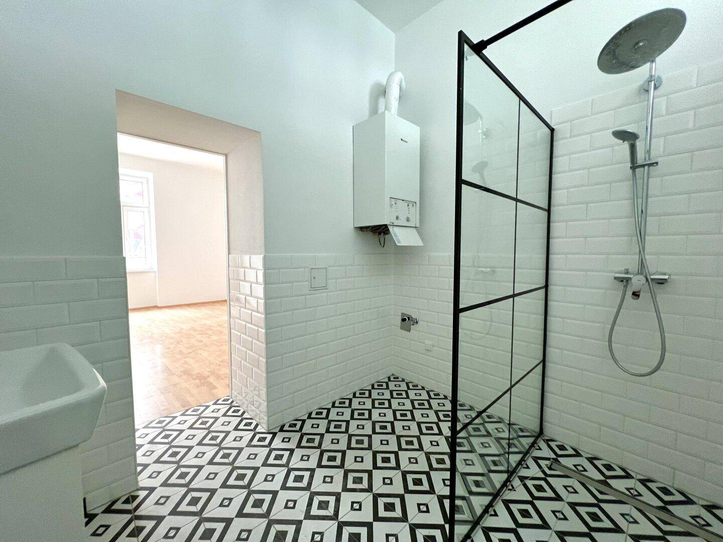 Modernes Badezimmer mit Duschkabine, geometrischen Fliesen und Wandheizung.
