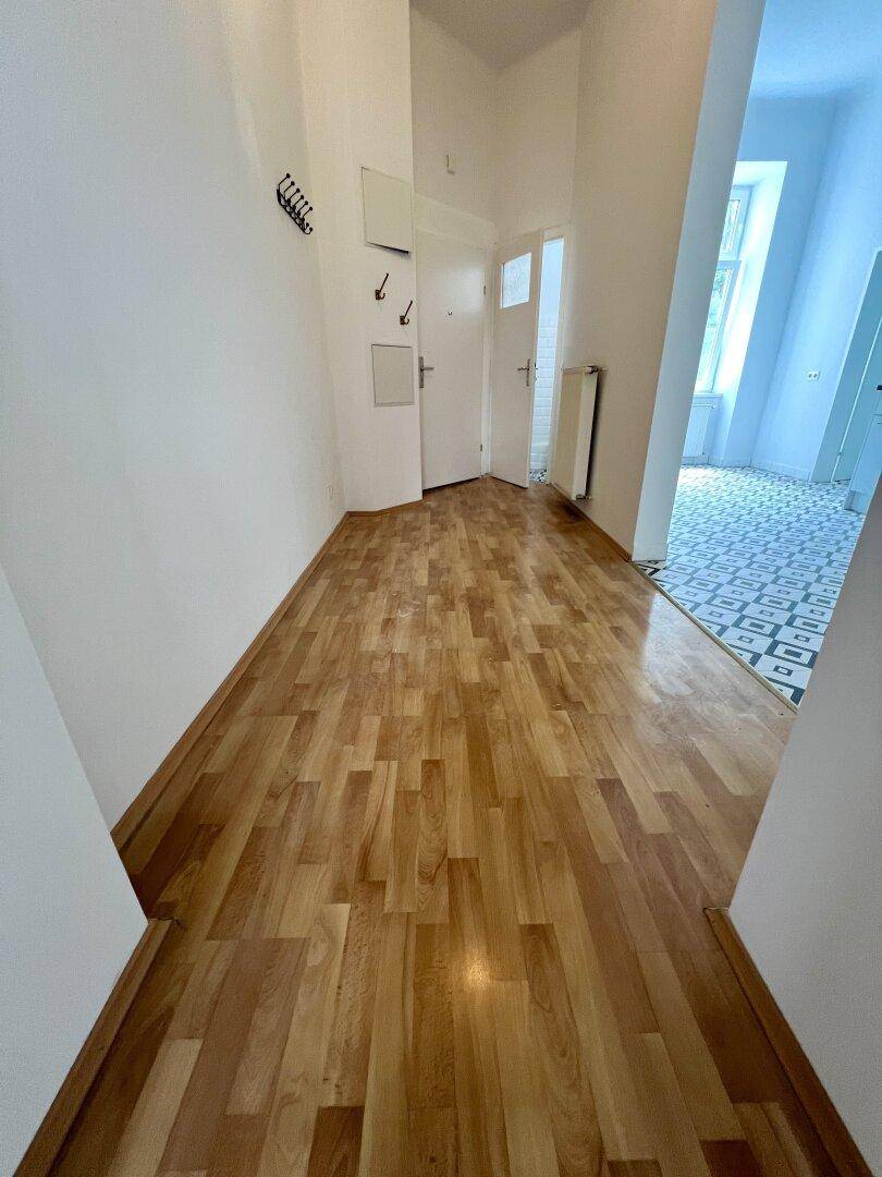 Heller Flur mit Holzparkettboden und Zugang zu weiteren Räumen der Wohnung.