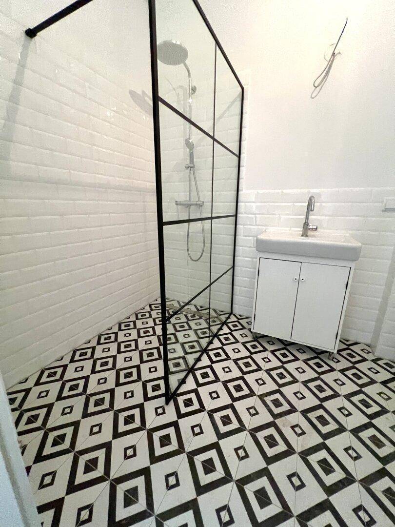 Modernes Badezimmer mit auffälligen schwarz-weißen Fliesen und einer begehbaren Dusche mit Glasabtrennung.