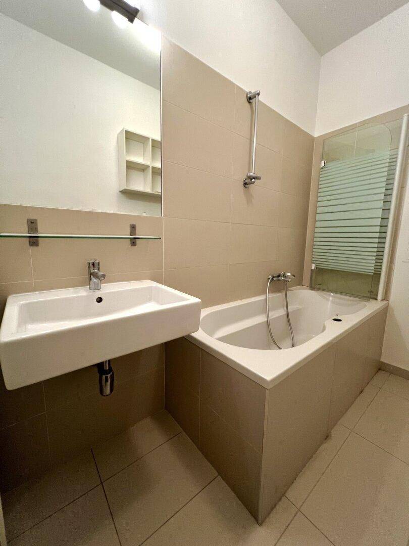 Modernes Badezimmer mit Badewanne, Waschbecken und beigefarbenen Fliesen.