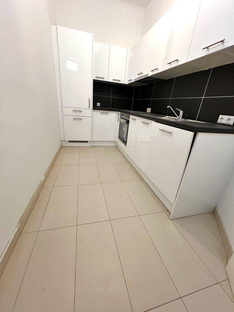 Kleine, moderne Küche mit weißen Hochglanzschränken und schwarzen Arbeitsplatten.