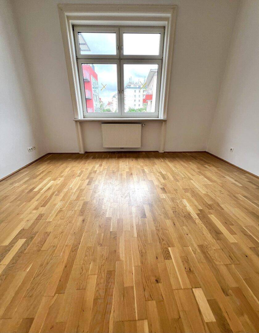 Helles Zimmer mit Parkettboden und Dachschräge, ideal als Schlaf- oder Wohnbereich.