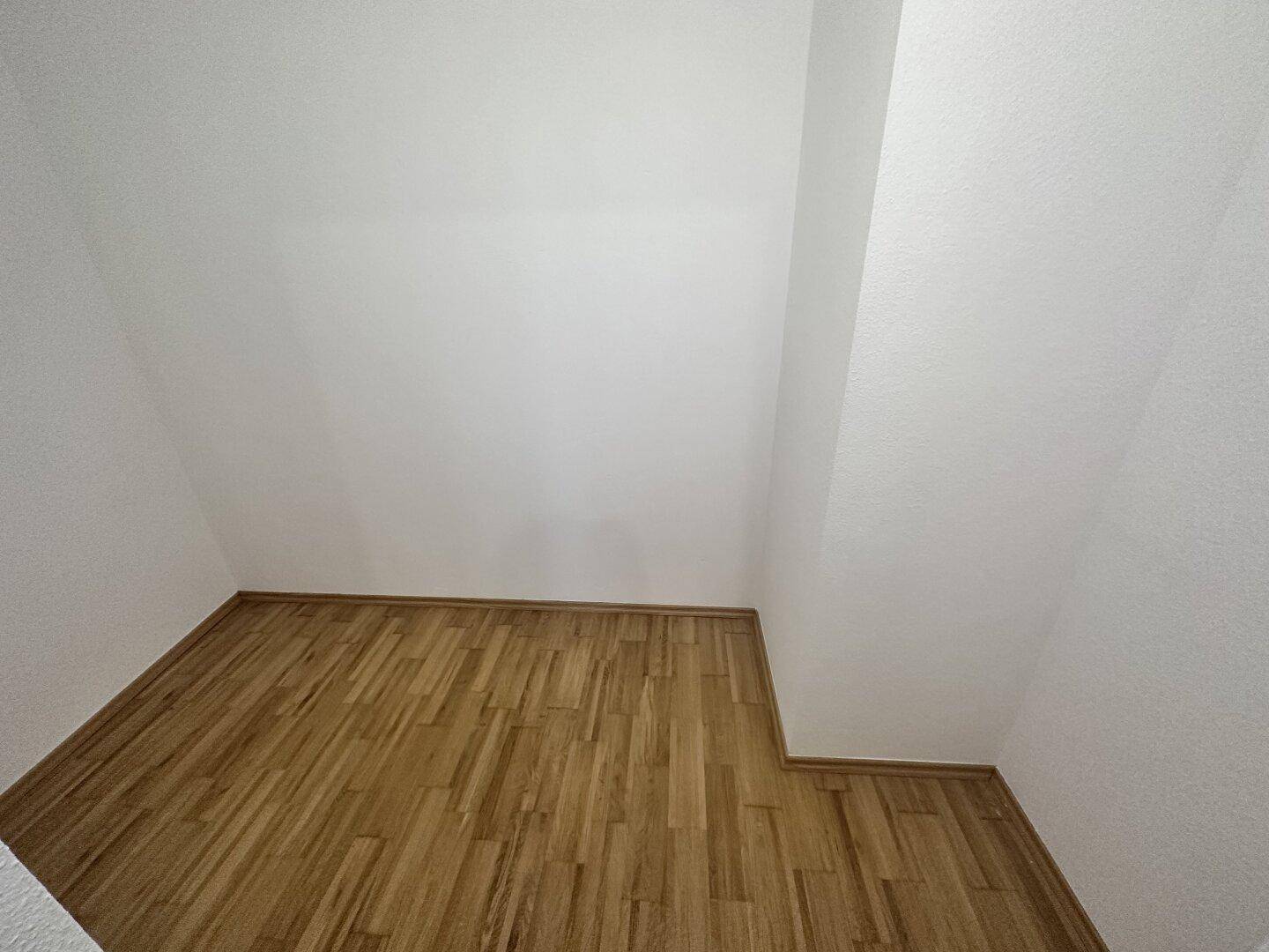 Heller Raum mit Parkettboden und weißen Wänden, bereit für die Einrichtung.