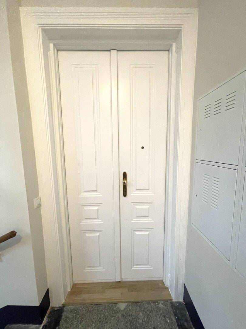 Eingangsbereich mit einer weißen Doppeltür und Schließfächern, führt in die Wohnung.