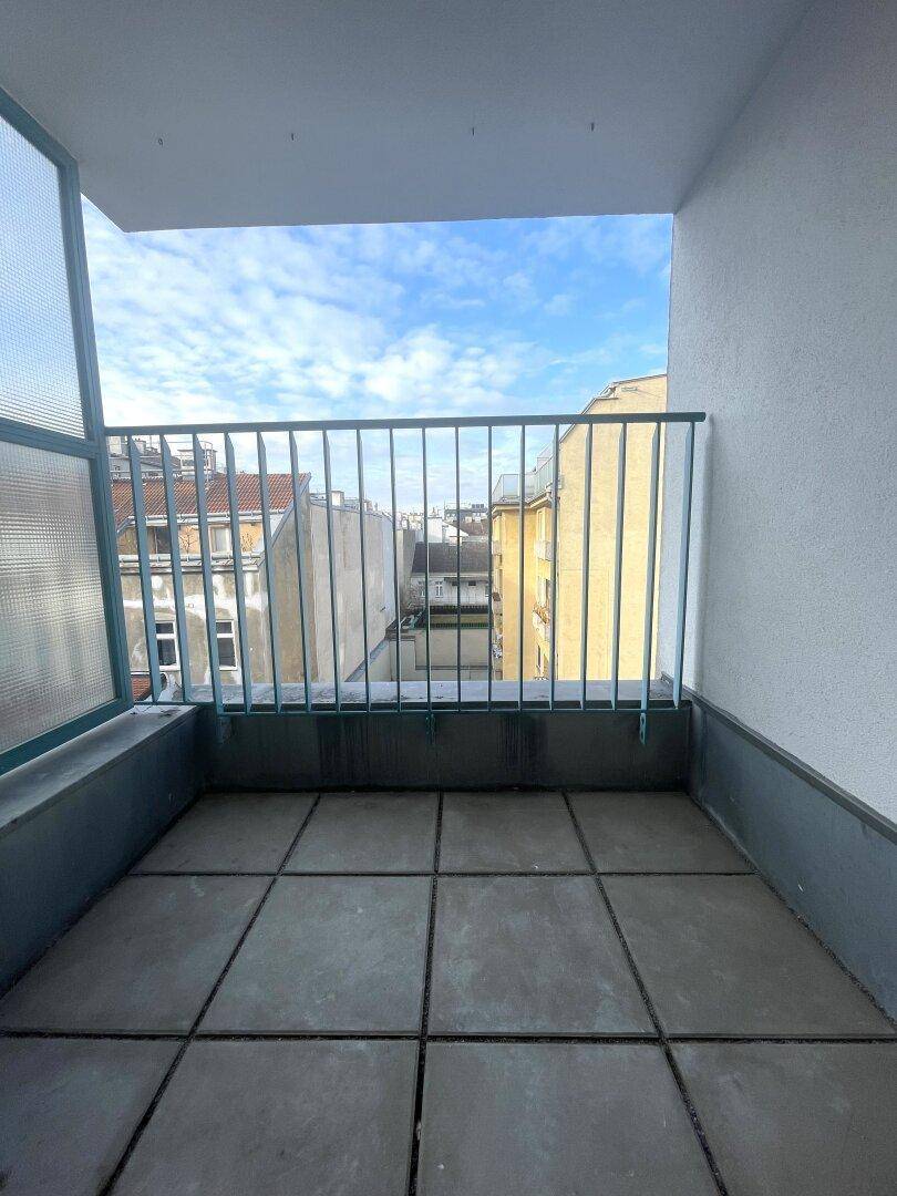 Balkon mit Fliesenboden und Blick auf die umliegenden Stadtgebäude.
