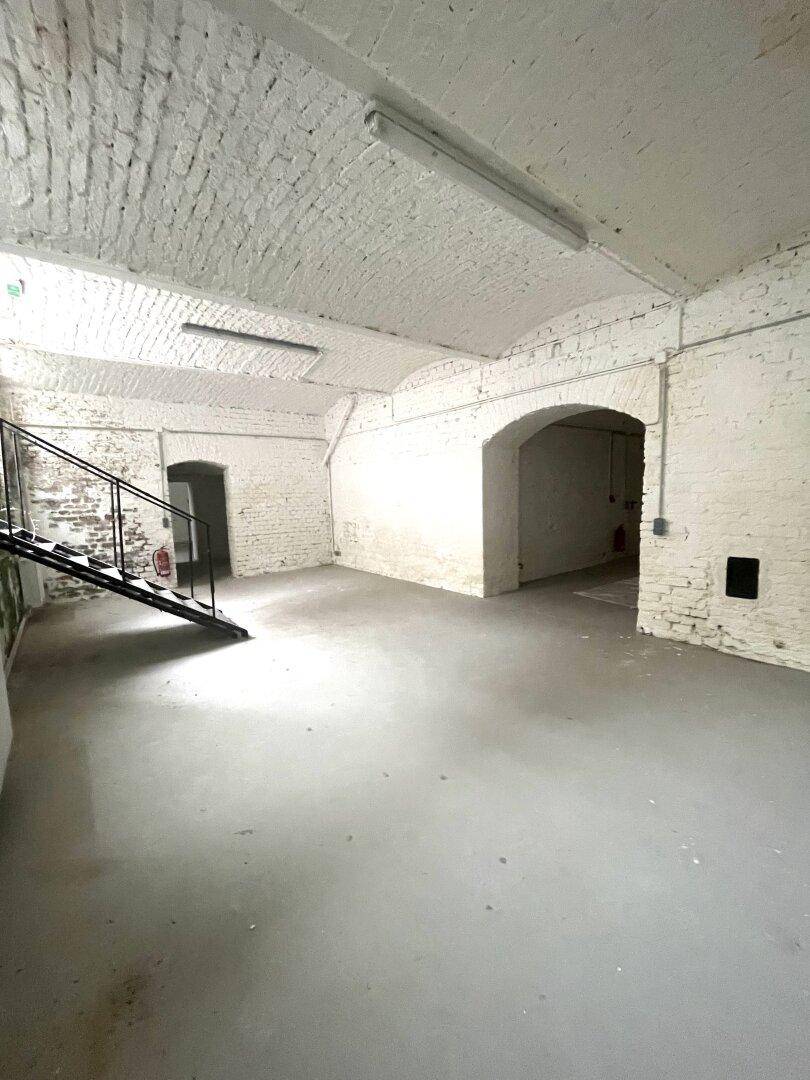 Geräumiger Kellerraum mit weiß gestrichenen Ziegelwänden, Gewölbedecke und Betontreppe.