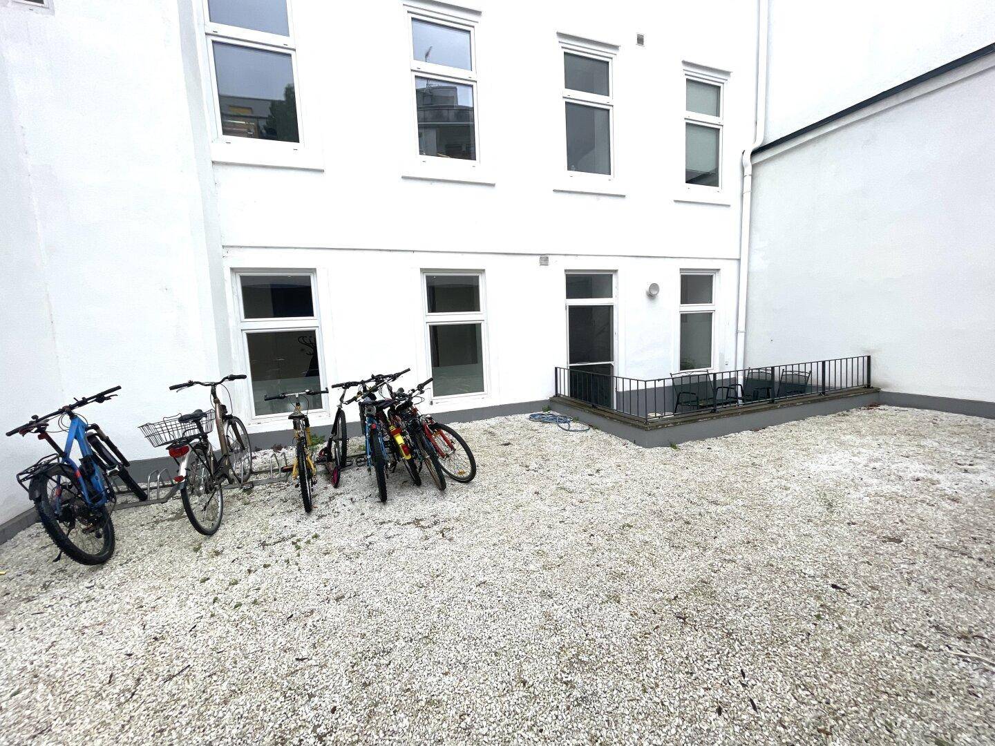 Gemeinschaftlicher Innenhof mit Fahrradabstellplätzen und Kiesboden, ideal für Bewohner.