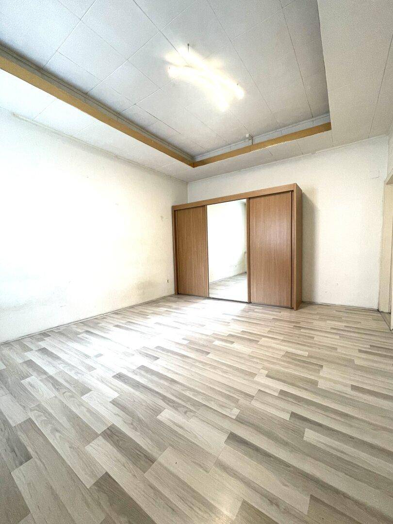 Geräumiges Zimmer mit Laminatboden und einem großen Spiegelschrank, ideal für Schlafzimmernutzung.