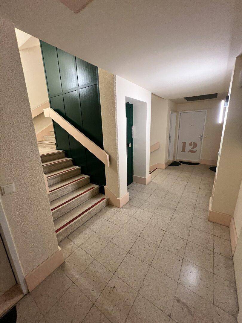 Treppenhaus und Flur eines Mehrfamilienhauses mit Fliesenboden und Zugang zu den Wohnungen.
