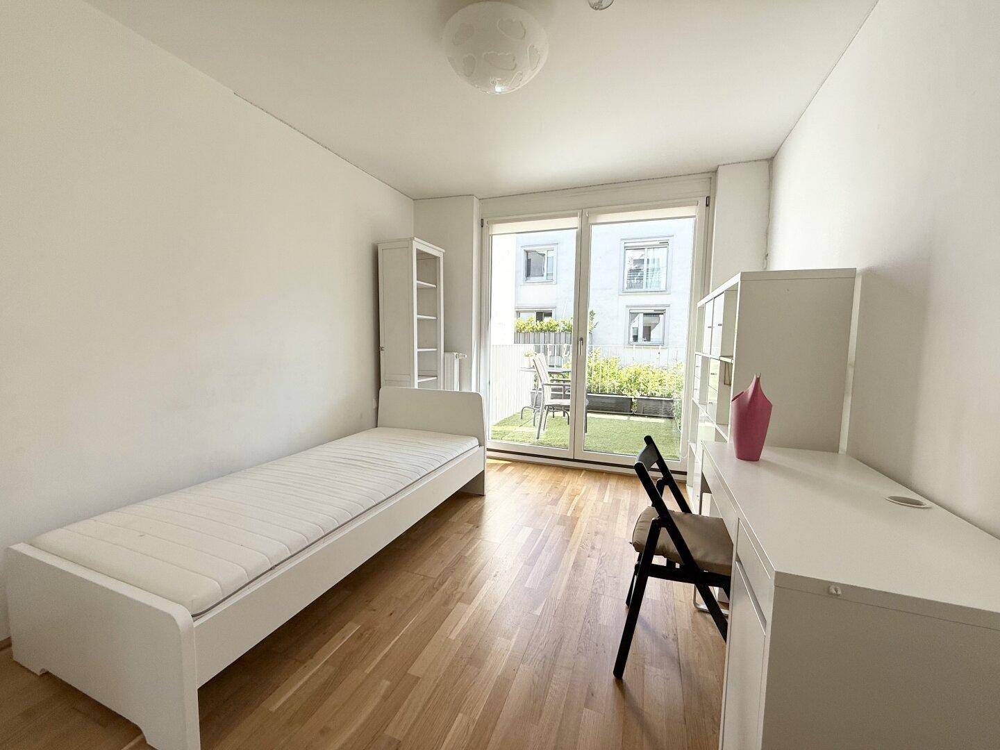 Helles Schlafzimmer mit Einzelbett, Schreibtisch und direktem Zugang zu einem kleinen Balkon.