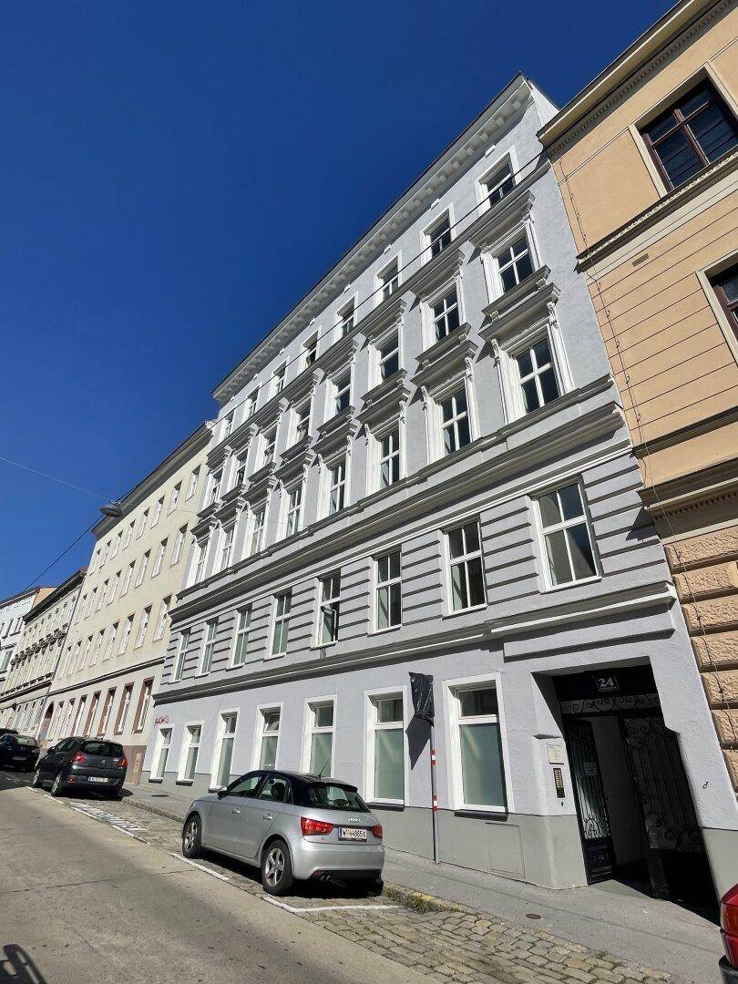 Mehrstöckiges Gebäude mit heller Fassade und klassischen Fenstern an einem sonnigen Tag.