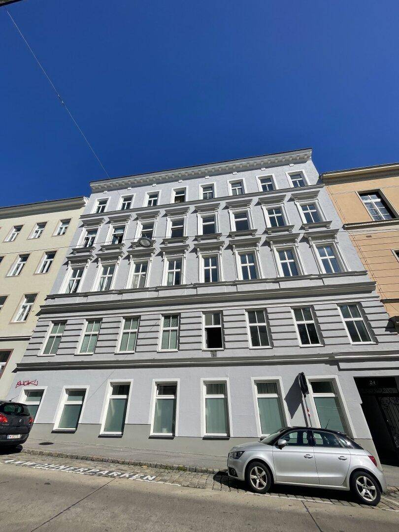 Klassische Fassade eines Altbaus mit vielen Fenstern und dekorativen Elementen.
