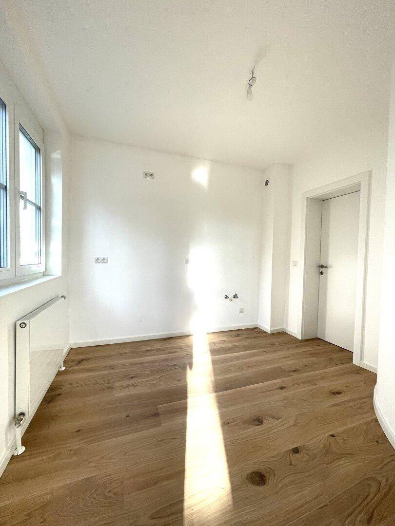Sonniger Schlafbereich mit Holzboden und weißen Wänden, bereit zur individuellen Gestaltung.