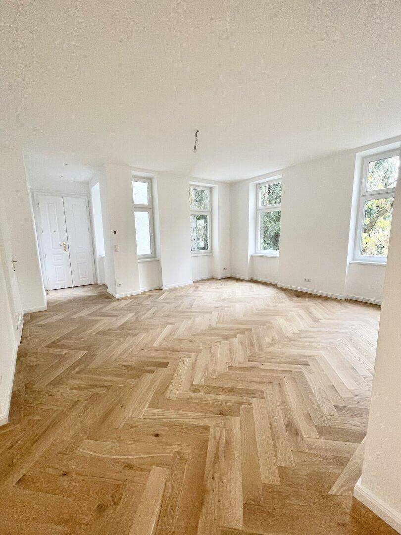 Großzügiger, leerer Raum mit neuem Fischgrätparkett, hohen Decken und viel Tageslicht.
