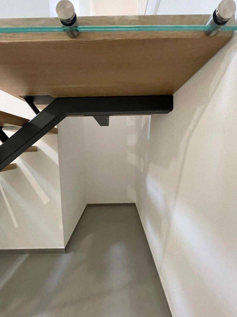 Stauraum unter der Treppe mit grauem Fliesenboden, ideal für zusätzlichen Platz.
