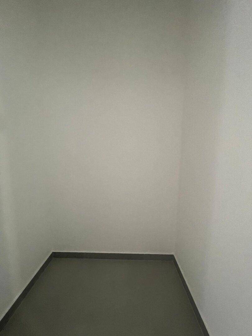 Kleiner Abstellraum mit grauem Fliesenboden und weißen Wänden für zusätzlichen Stauraum.
