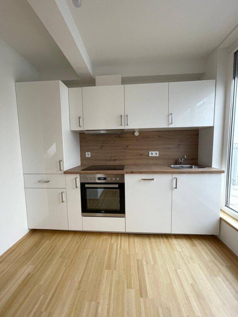 Moderne Einbauküche mit weißen Hochglanzfronten, Holzarbeitsplatte und integrierten Geräten.