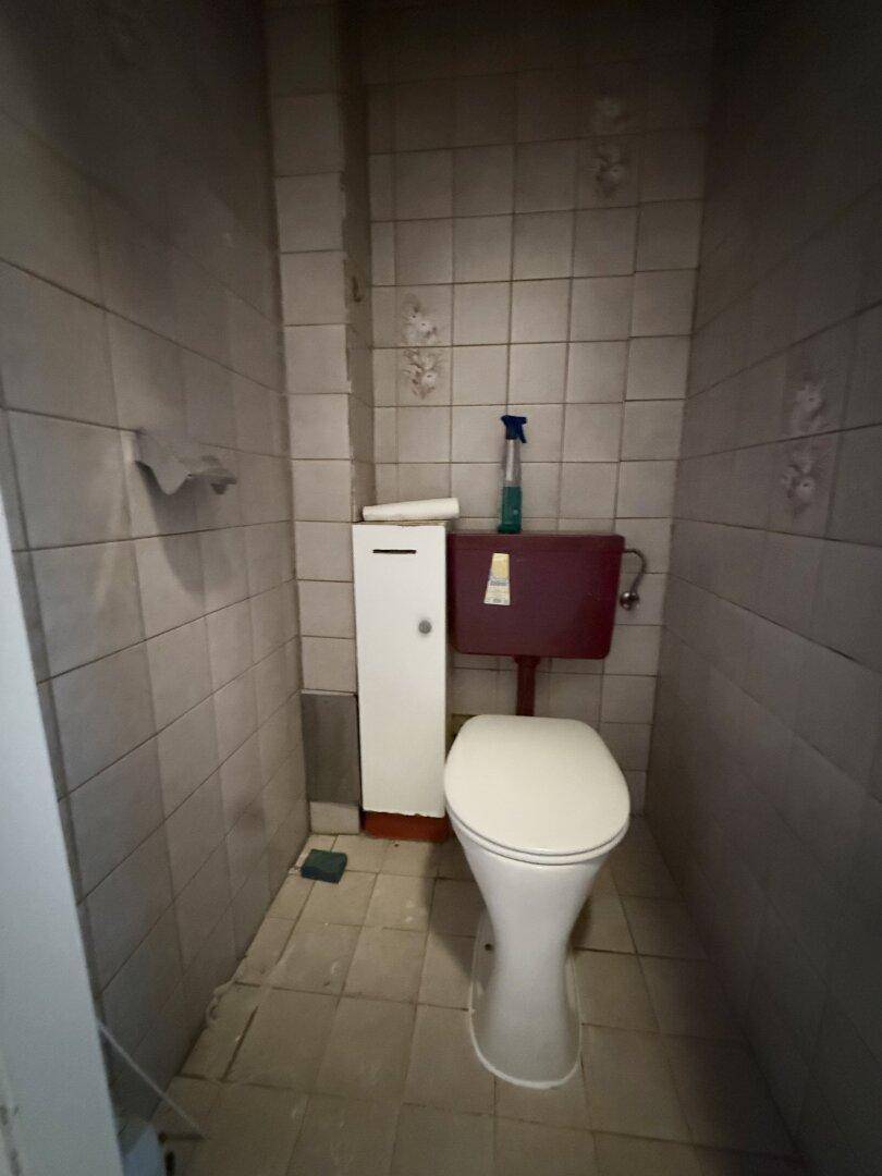 Kleines WC mit gefliesten Wänden und Boden, ausgestattet mit einer Toilette.