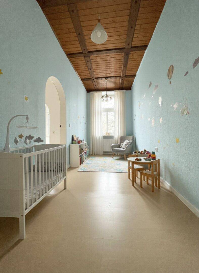 Freundliches Kinderzimmer mit hellem Boden, blauen Wänden und einer charmanten Holzbalkendecke.