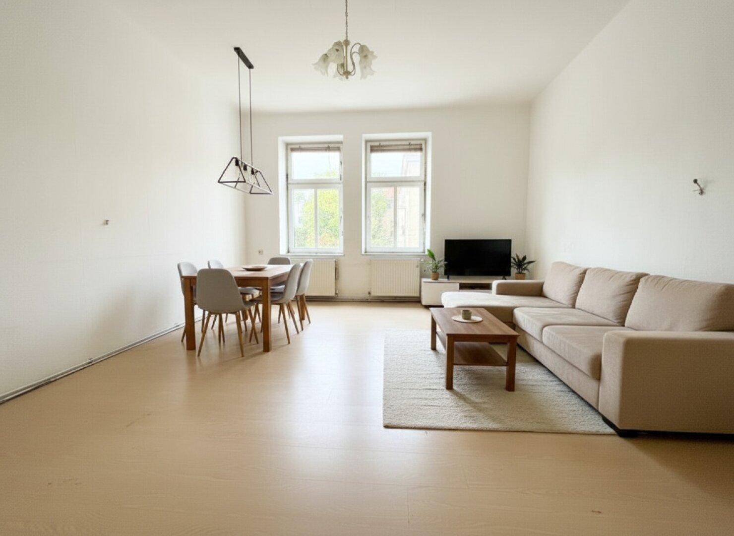 Heller Wohn-Essbereich mit modernem Sofa, Esstisch und stilvoller Beleuchtung.