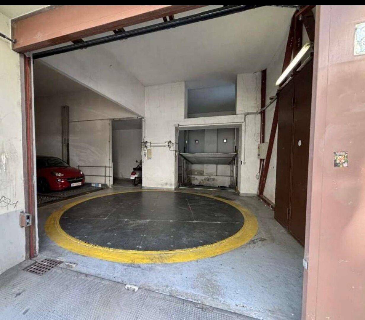 Innenansicht einer Tiefgarage mit Autodrehbühne und Hebebühne für Fahrzeuge.