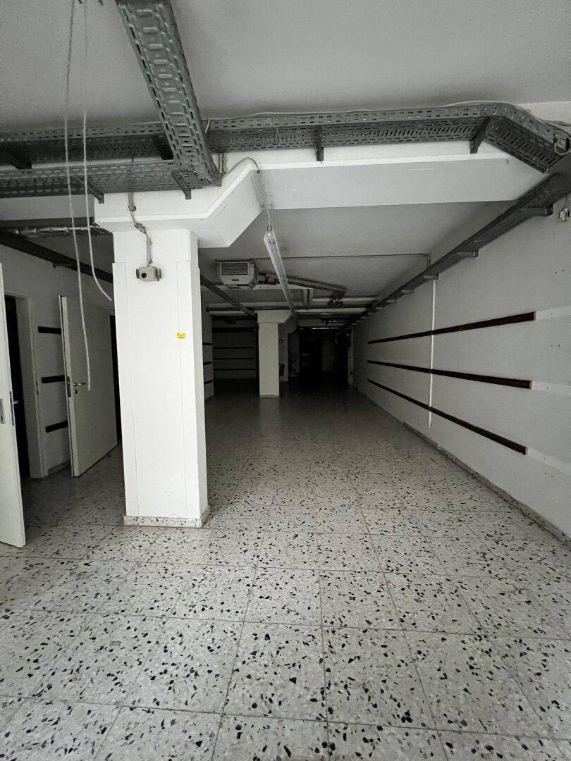 Geräumiger Lagerraum im Untergeschoss mit sichtbaren Installationen und Terrazzoboden.