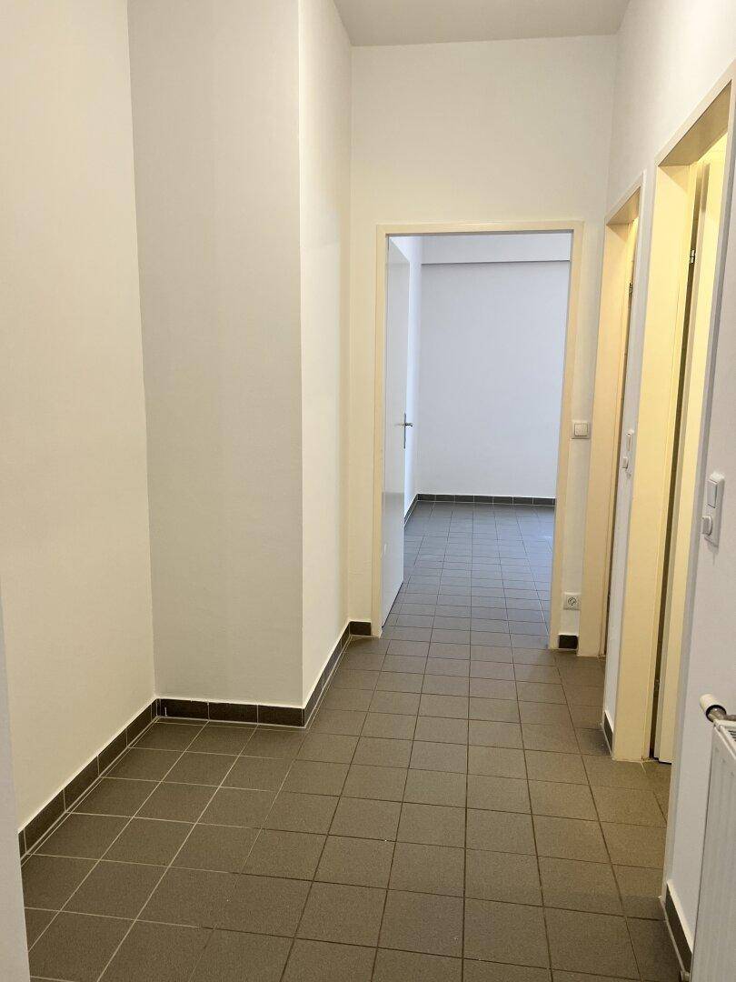 Heller Flur mit Fliesenboden und Zugang zu mehreren Zimmern der Wohnung.