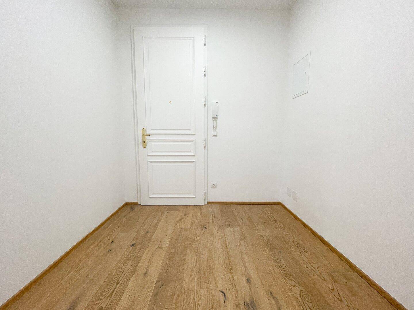 Heller Eingangsbereich mit Holztür und Parkettboden, der einen freundlichen Empfang bietet.
