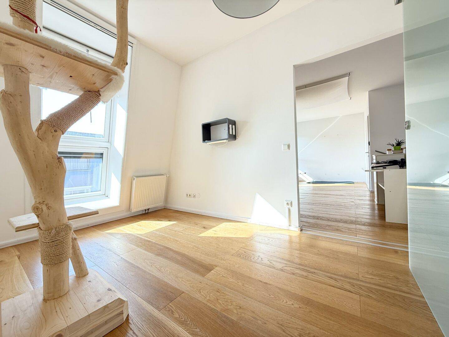 Helles Zimmer mit Holzboden und großem Fenster, ideal für ein Schlafzimmer oder Hobbyraum.