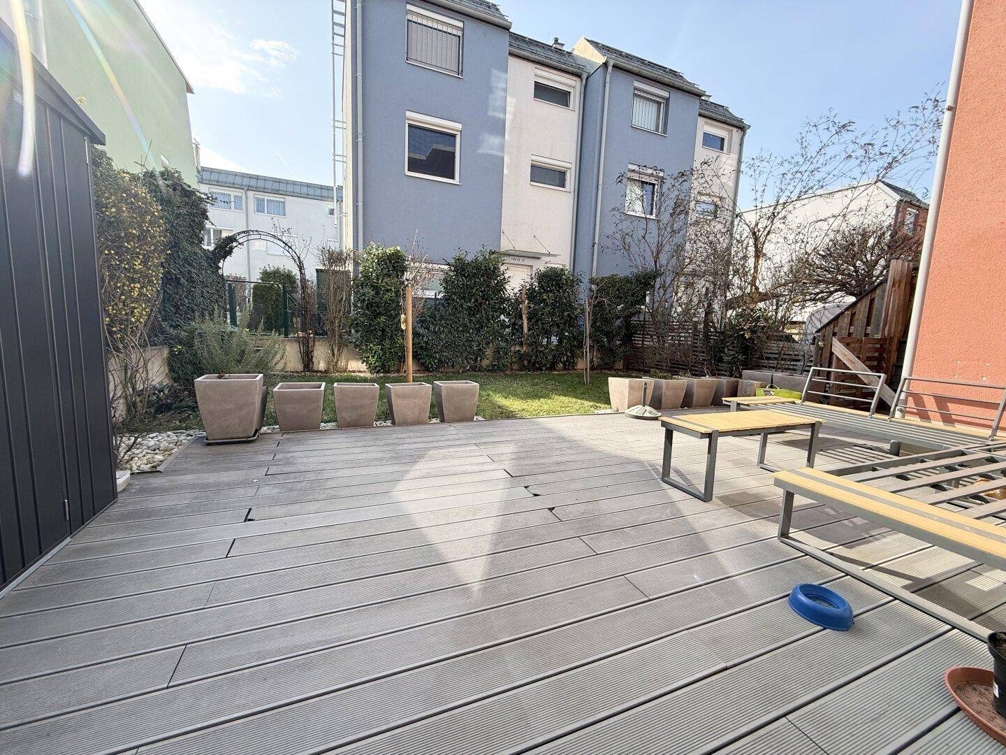 Geräumige Holzterrasse mit Sitzgelegenheiten und Blick auf den Garten, ideal für Outdoor-Aktivitäten.