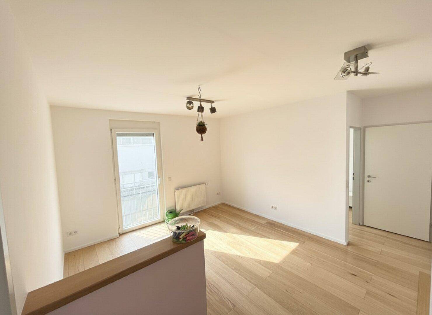Heller Raum im Obergeschoss mit Holzboden und Zugang zu einem französischen Balkon.