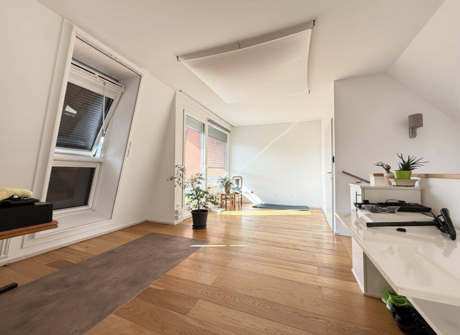 Geräumiger Dachbodenraum mit Holzboden und Dachfenstern, bietet vielseitige Nutzungsmöglichkeiten.