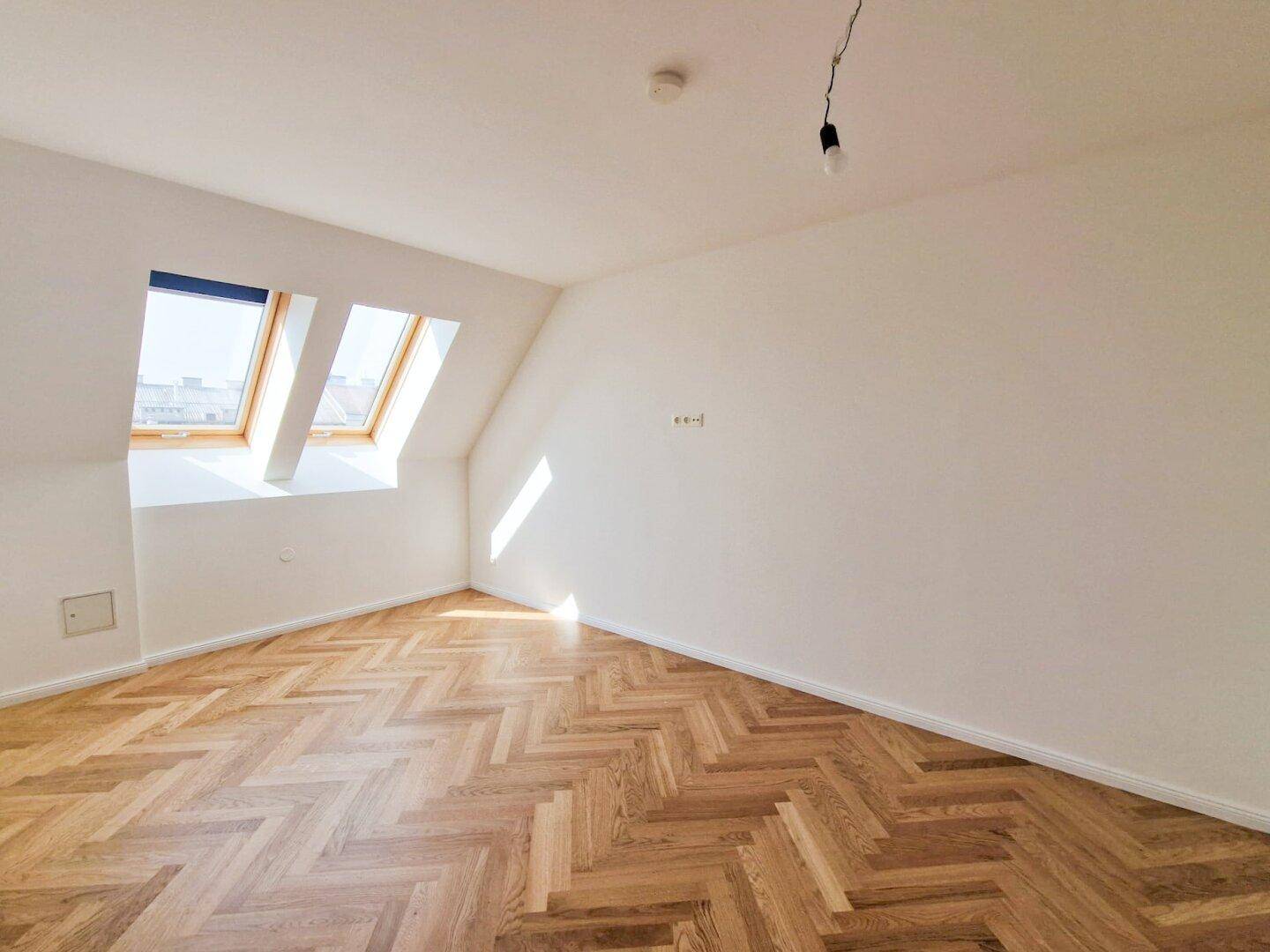 Helles Zimmer mit Fischgrätparkett und zwei Dachfenstern, ideal als Schlaf- oder Arbeitszimmer nutzbar.