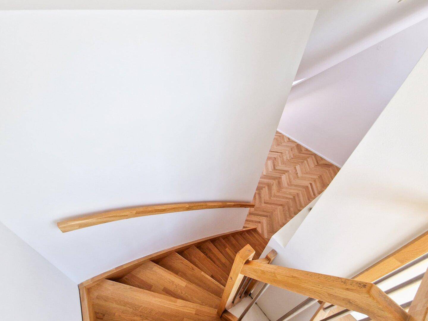 Elegante Holztreppe mit geschwungenem Handlauf, die die verschiedenen Etagen stilvoll verbindet.