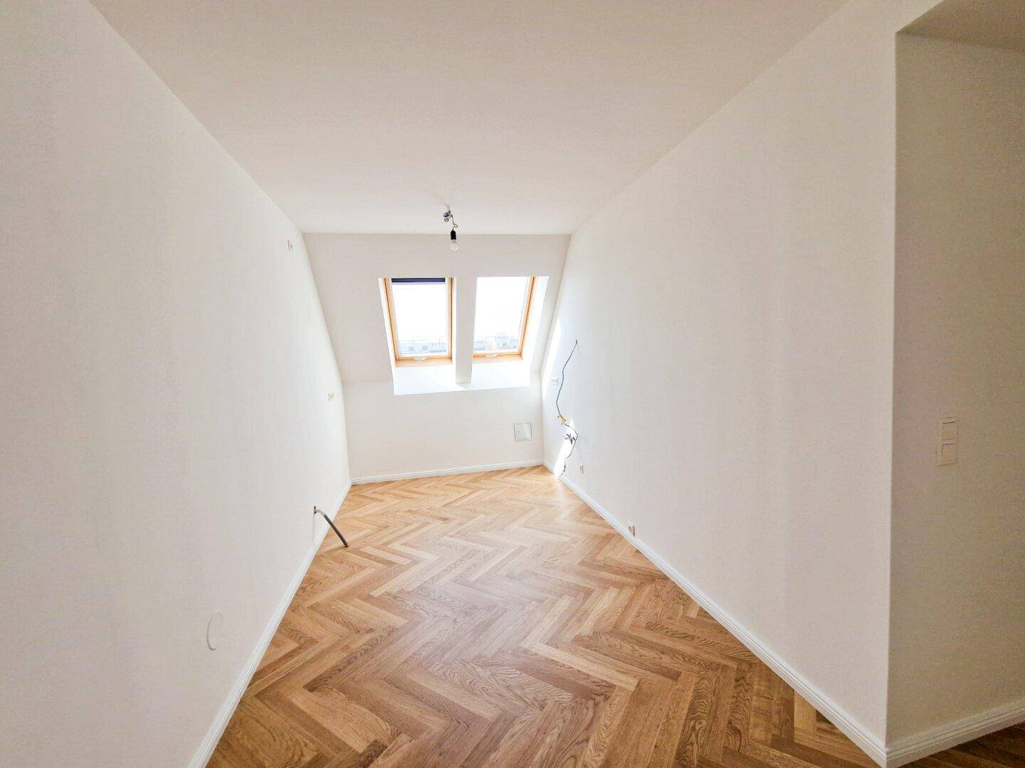 Gemütliches Schlafzimmer mit Fischgrätparkett und zwei Dachfenstern für viel Tageslicht und frische Luft.