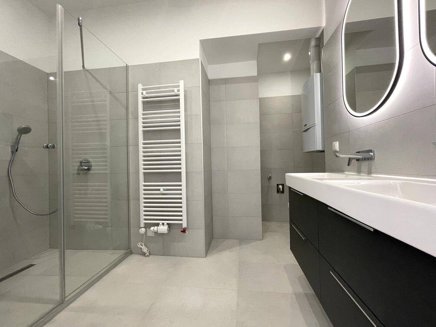 Modernes Badezimmer mit großer begehbarer Dusche, Doppelwaschbecken und beheiztem Handtuchhalter.