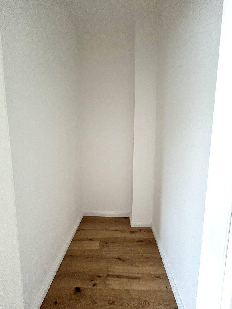 Kleiner, leerer Abstellraum mit Holzboden, ideal für zusätzlichen Stauraum oder als begehbarer Kleiderschrank.