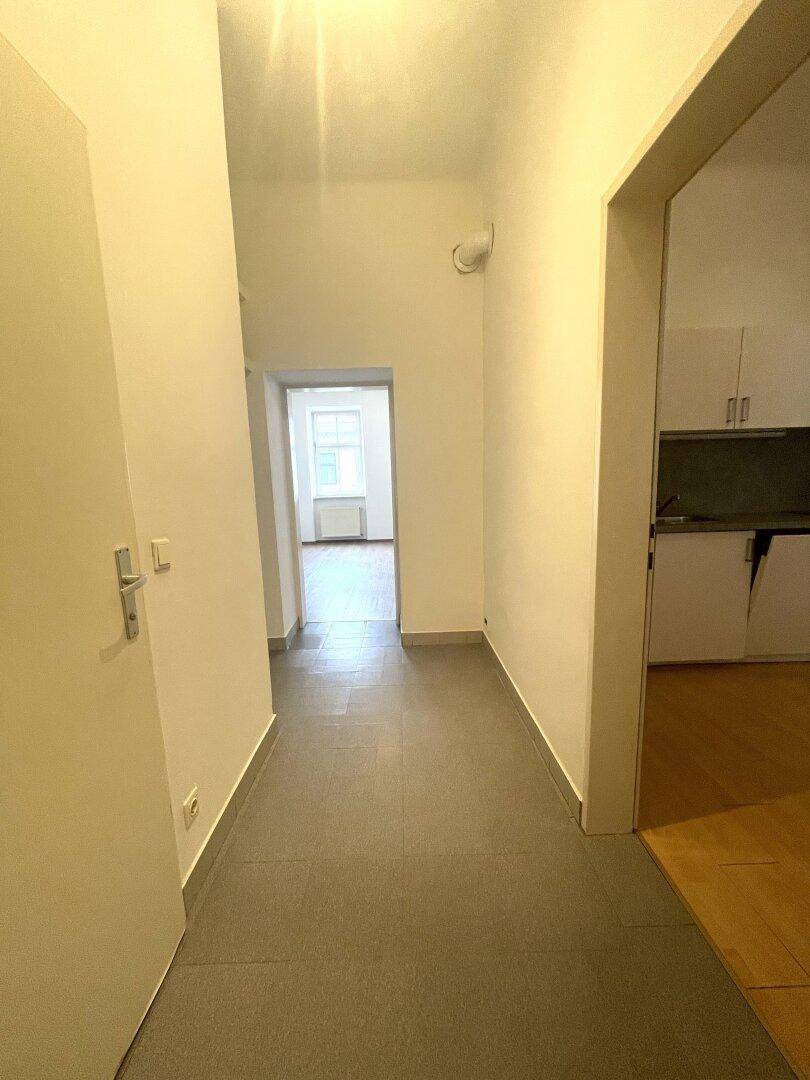 Heller Flur mit Fliesenboden, der zu weiteren Räumen der Wohnung führt.