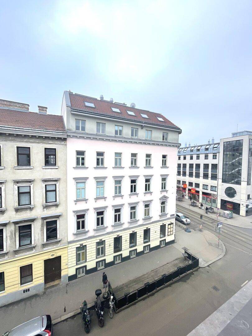 Blick auf ein Wohngebäude an einer städtischen Straße mit weiteren Gebäuden im Hintergrund.
